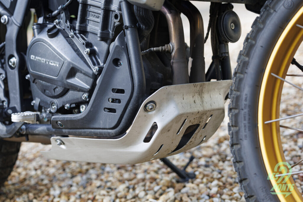 Forcément, la finition de la partie visible du moteur n’est pas aussi soignée que sur les customs QJMotor. La présence d’un sabot ajoute du cachet.